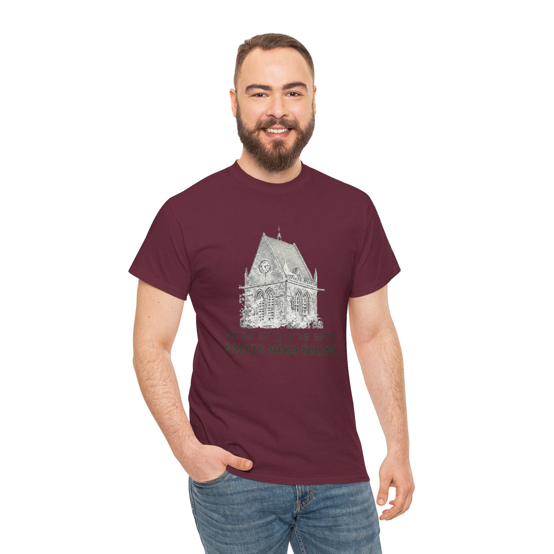 Maroon T-shirt by Veteran owned, featuring a church graphic with coordinates and "Sainte-Mère-Église" text, worn with jeans.