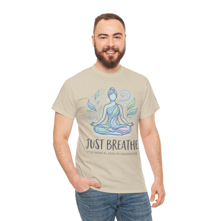 Beige T-shirt with "Just Breathe" design by Veteran owned, featuring a meditating figure with surrounding leaf pattern, worn with jeans.