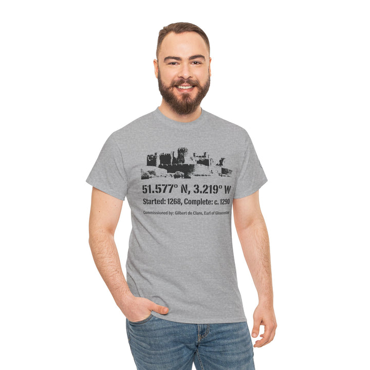 Gray Caerphilly Castle T-shirt by S&amp;W Gallus, featuring castle graphic with historical coordinates, worn with jeans by smiling man.