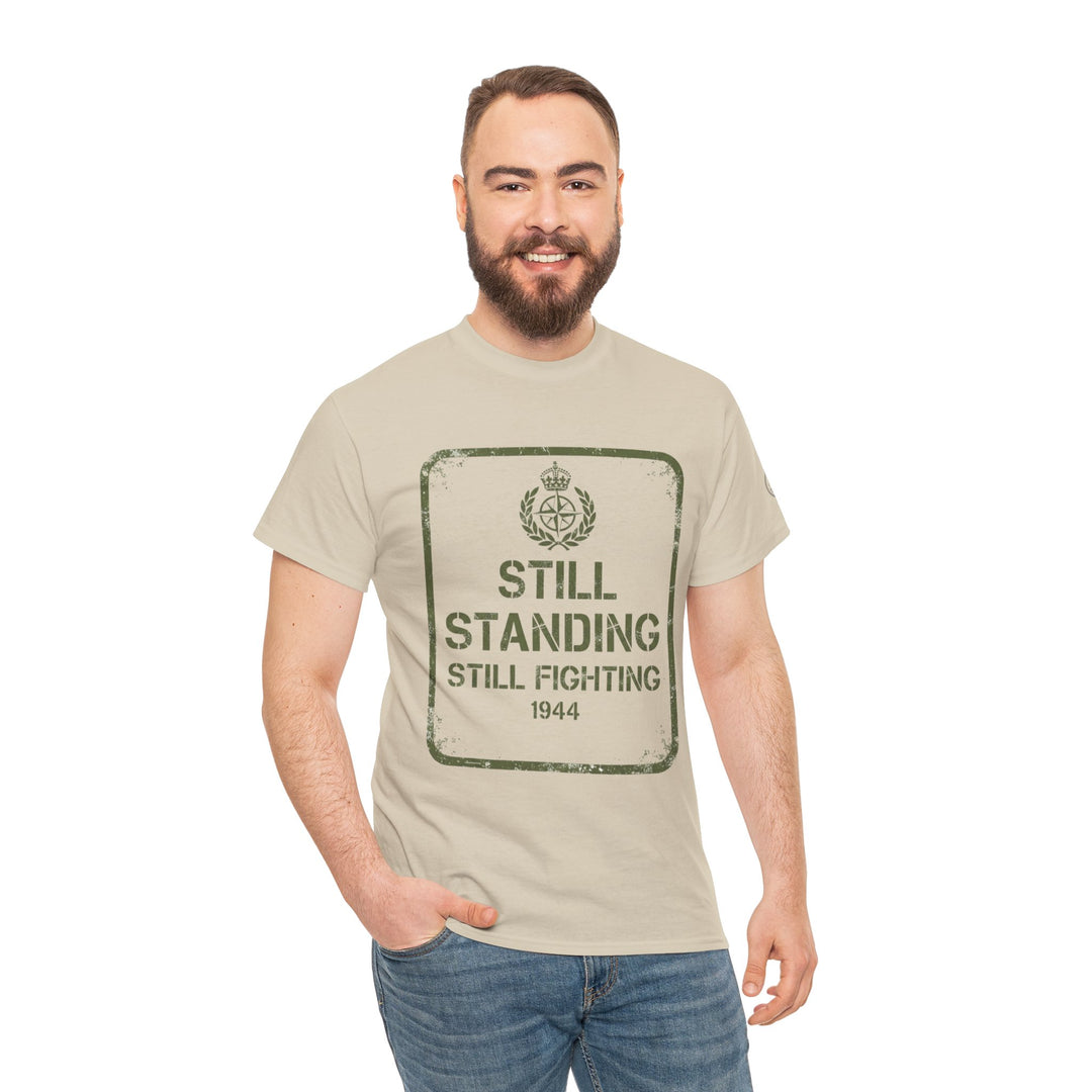 Beige tee shirt by S&amp;W Gallus featuring a "Still Standing" graphic, paired with blue jeans.