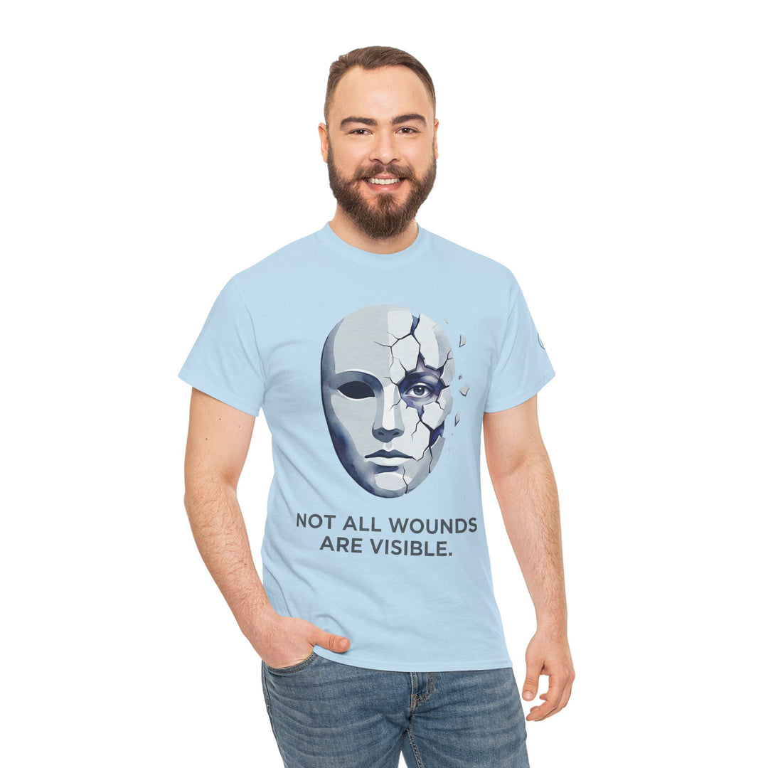 Light blue t-shirt by Veteran owned, featuring a cracked mask and the text "Not All Wounds Are Visible", on a person wearing jeans.