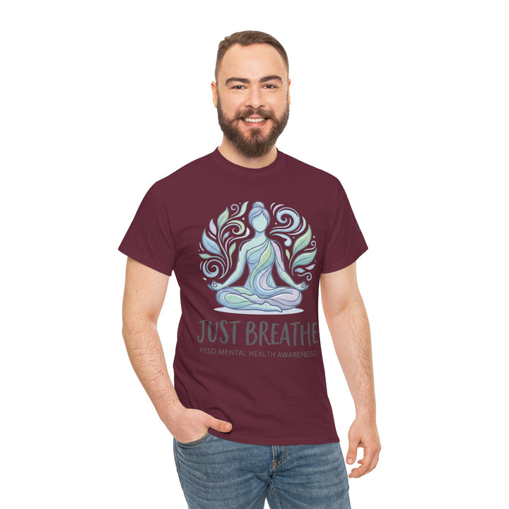 Maroon t-shirt by Veteran owned, featuring a meditating figure surrounded by leaves, with "Just Breathe" text, worn with jeans.