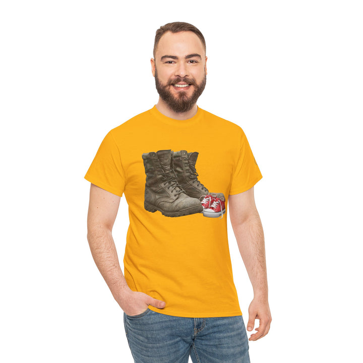 Yellow t-shirt from S&amp;W Gallus, featuring a graphic of military boots and baby shoes, styled with jeans and a smiling man.