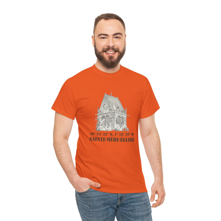 Orange t-shirt by Veteran owned, featuring a Sainte-Mère-Église church graphic and coordinates, worn with blue jeans.