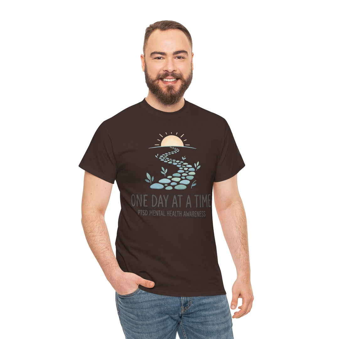 Brown "One Day at a Time" PTSD awareness t-shirt by Veteran owned, with a stone path graphic and worn with jeans.
