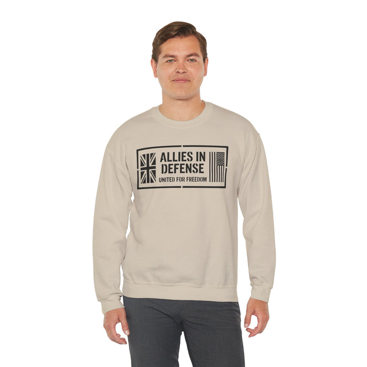 Beige crewneck sweatshirt with "Allies in Defense" graphic by S&amp;W Gallus, featuring UK and US flag details, paired with grey pants.