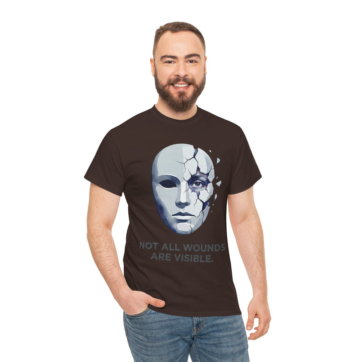 Brown t-shirt by Veteran owned, featuring a cracked mask graphic and the text "Not All Wounds Are Visible", worn with blue jeans.