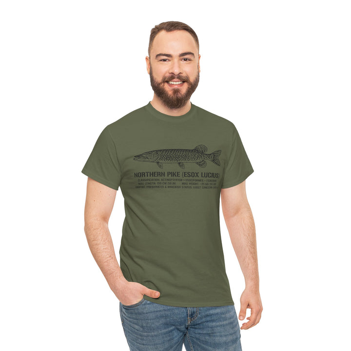 Olive green Northern Pike T-shirt by S&amp;W Gallus, featuring a fish illustration and scientific classification, worn with jeans by a smiling man.
